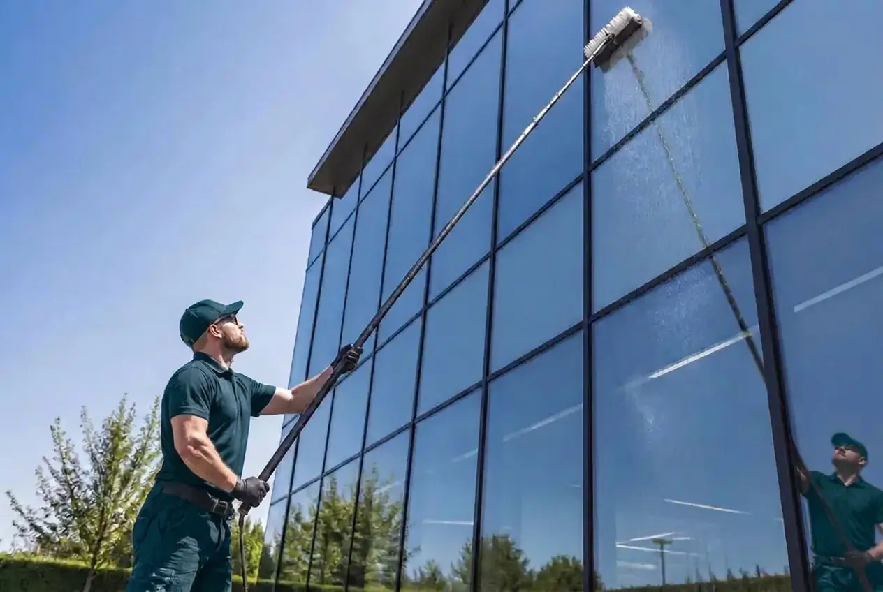 Glasreiniger reinigt eine Glasfassade eines Bürogebäudes mit einer Teleskopstange und Osmoseanlage